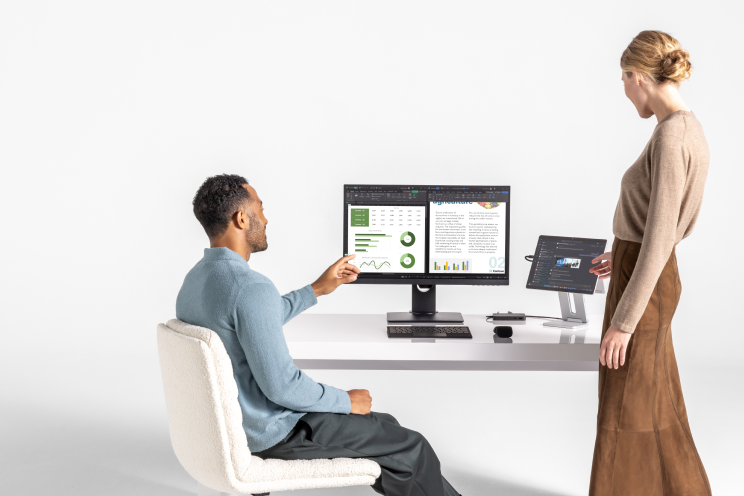 Two people looking at a display monitor and tablet.