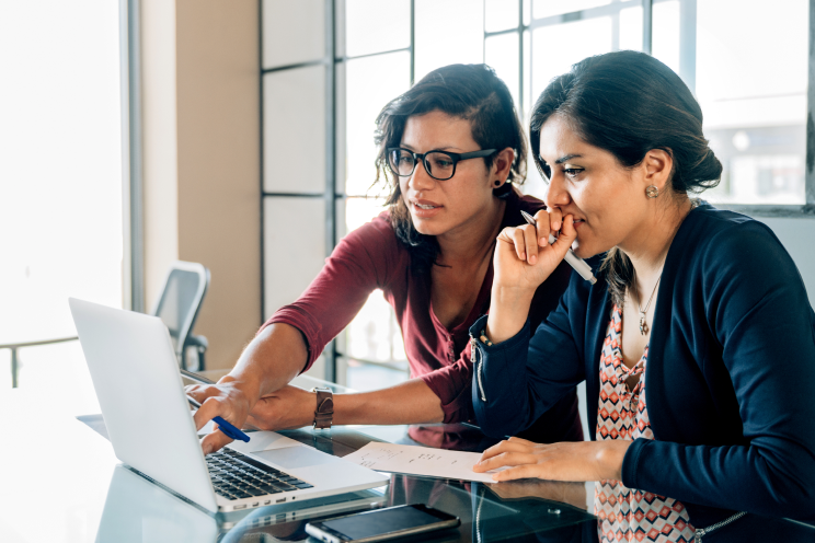 Two people working on a laptop together.