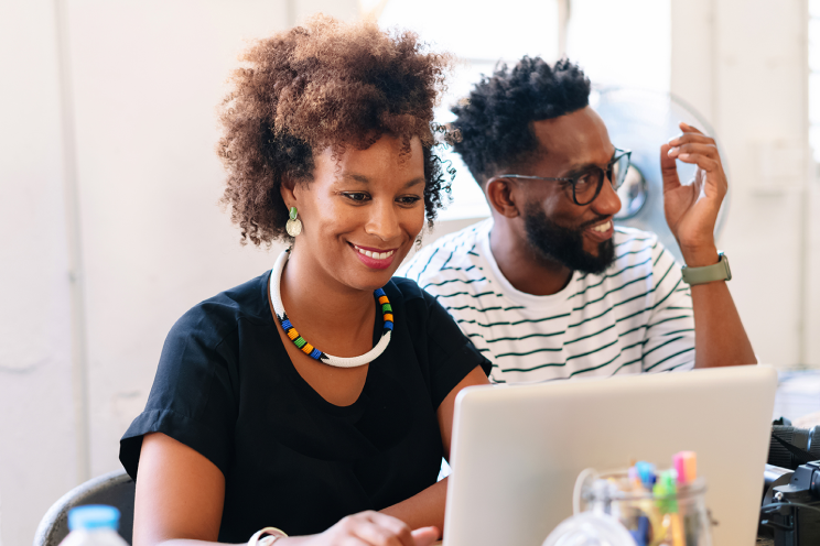 Two people seated working on a laptop.