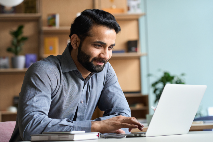 Person working on a laptop and smiling.