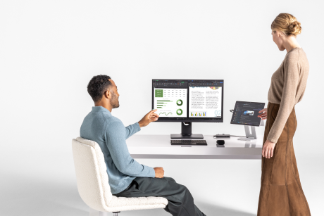 Two people looking at a display monitor and tablet.