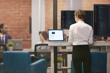 A person working on a laptop at a standing desk