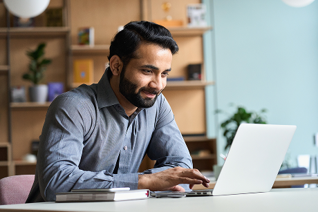Person working on a laptop and smiling.