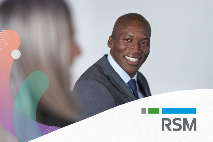 A seated person smiling at another person.