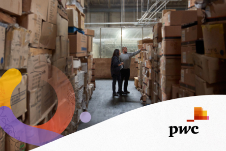 Two people in a warehouse with piles of boxes
