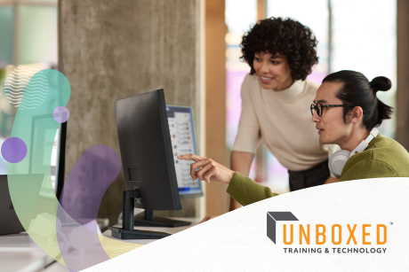 Two people working on a dual monitor computer.