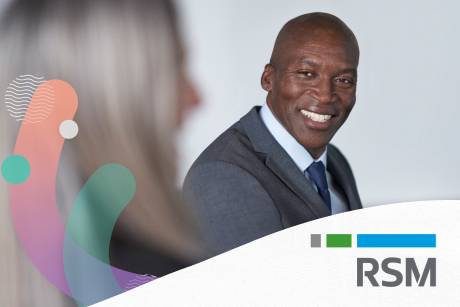 A seated person smiling at another person.