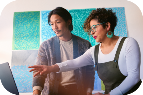 Duas pessoas apontando para a tela de um laptop.