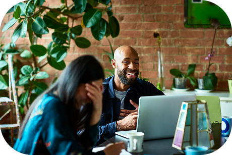 Two people laughing with a laptop open