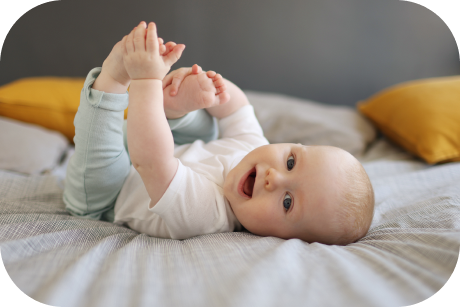 A smiling baby holding its feet.