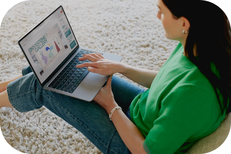 A person sitting on a rug working on a laptop