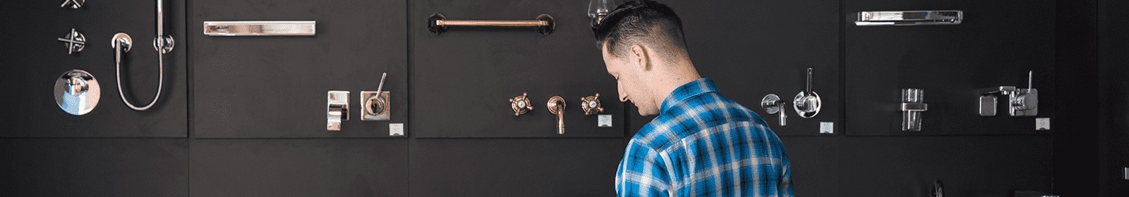 A retail employee stands in front of a wall of plumbing fixtures