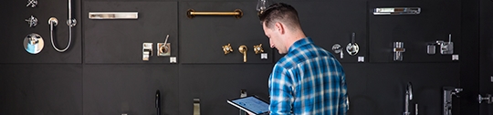 A retail employee stands in front of a wall of plumbing fixtures