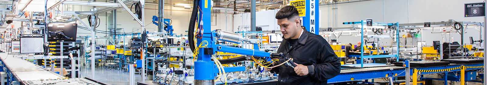 An industrial worker operates a large machine by hand