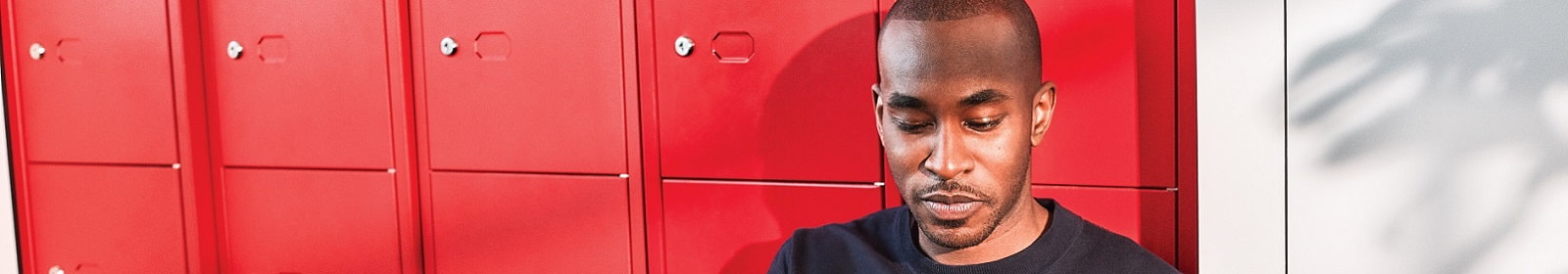 A man uses his tablet by a row of lockers