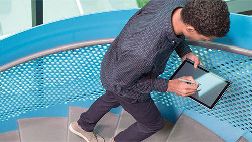 Man climbing stairs while working on a Surface tablet