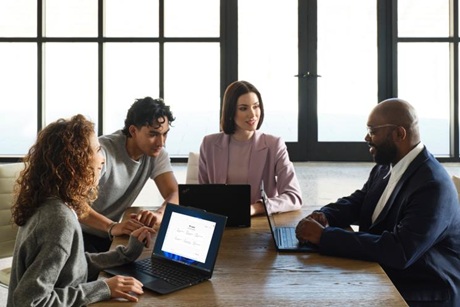 A group of people with laptops gathered around a table.