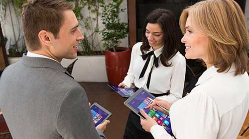Man and two female coworkers talking and working on tablets