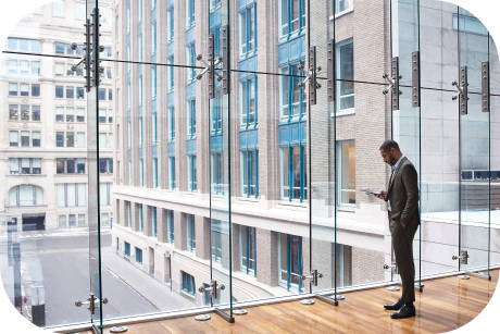 Person standing by glass windows looking at a cell phone