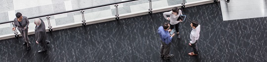 Employees chat on an elevated walkway in an office building