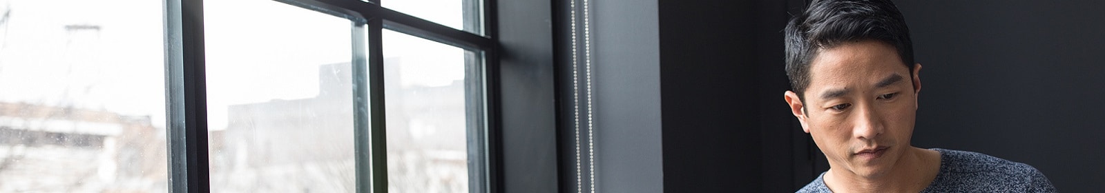 A man sitting next to a window works on his tablet