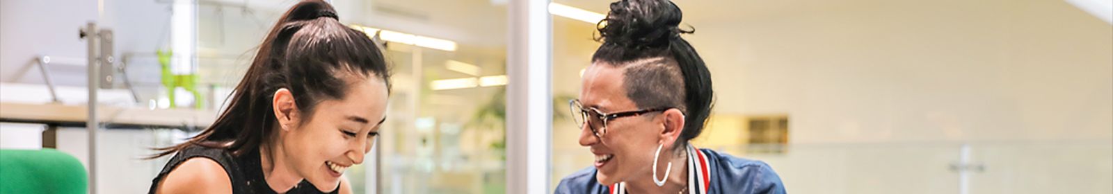 Two women laugh as they work together