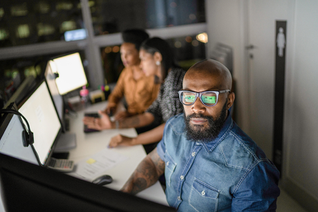 A person sitting at a desk looking at a computer monitor