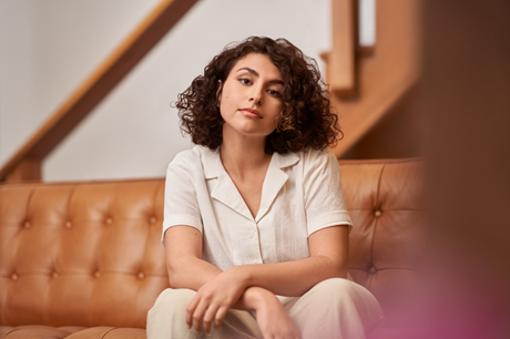 Person with curly hair in office sits on leather couch