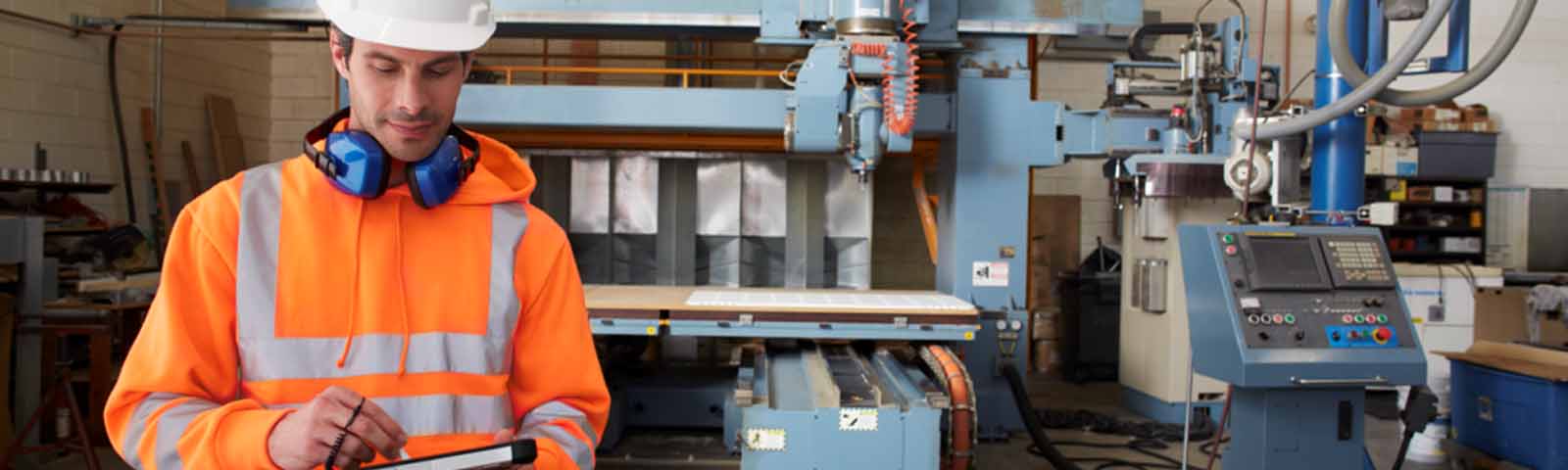 Man in orange jacket and white helmet looking at a computer tablet