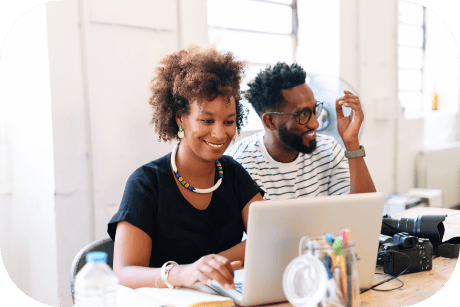 Two people smiling while working on a laptop