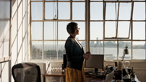 Woman standing in office looking out window