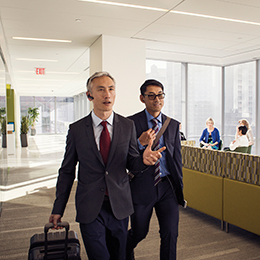 Two business men walking down hallway talking