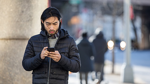 Man standing on street using a smartphone