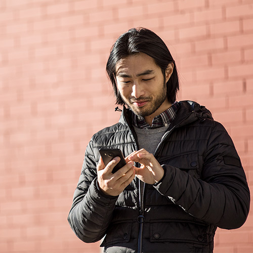 Man standing outside working on cellular device
