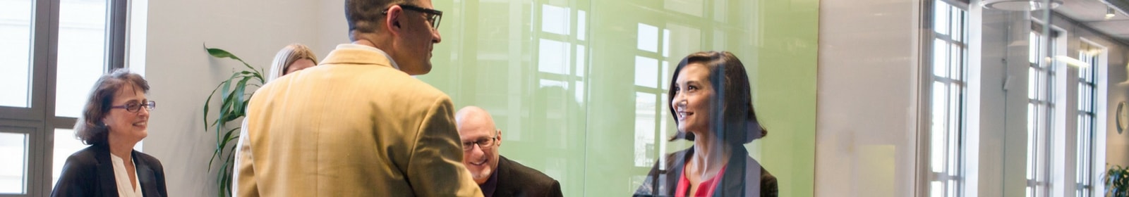 Group of people welcomes client to meeting. 