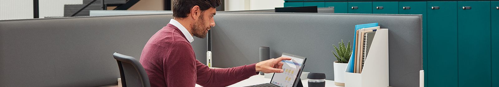 A man works on a tablet device at a desk 