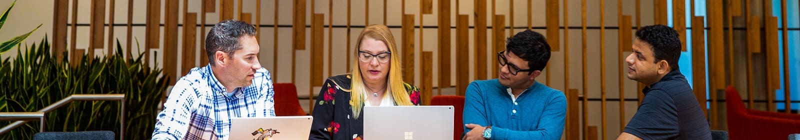 Four tech workers meet in an office common area