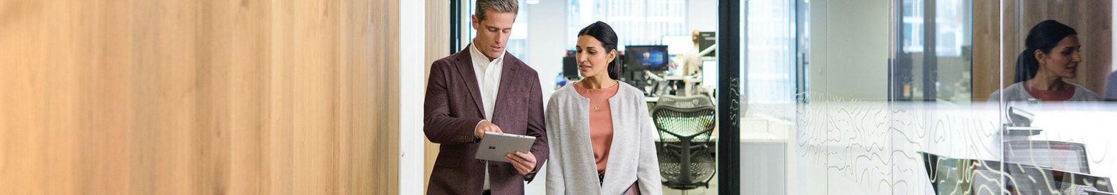 Two people review information on a Surface device