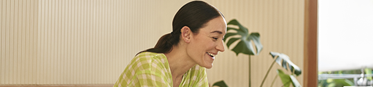 Woman sitting in kitchen working on laptop