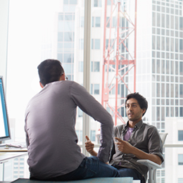 Two coworkers having discussion near computer