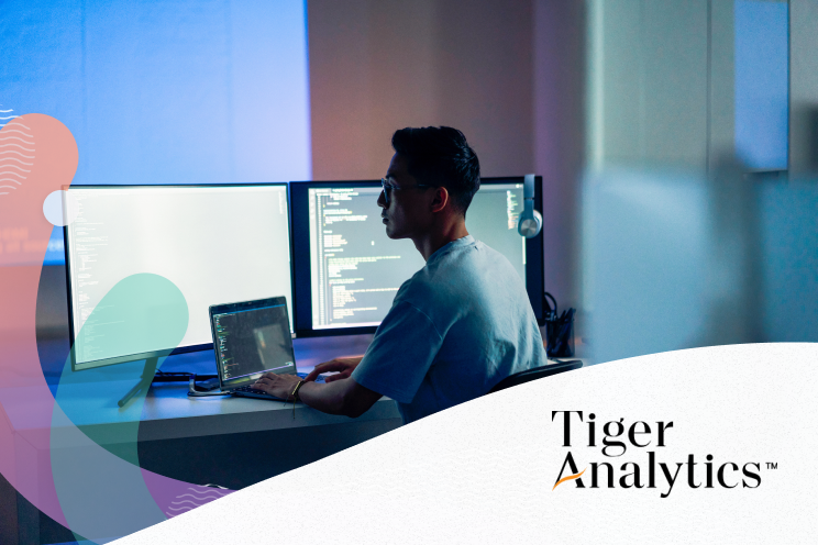 Person seated at a desk working on multiple monitors.