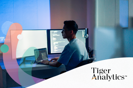 Person seated at a desk working on multiple monitors.