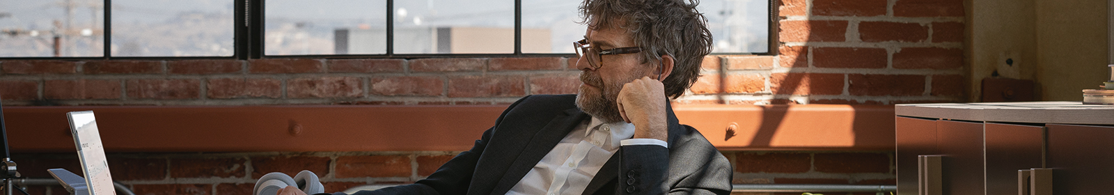 A seated man looks at a laptop screen