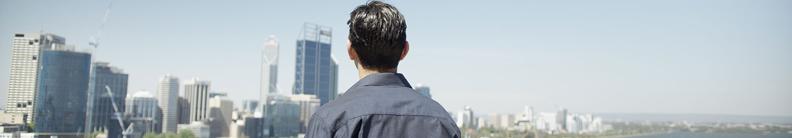 Man standing outside on balcony looking off in the distance