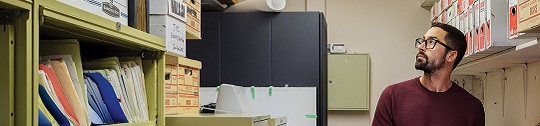 A man looks for files in an office storage room