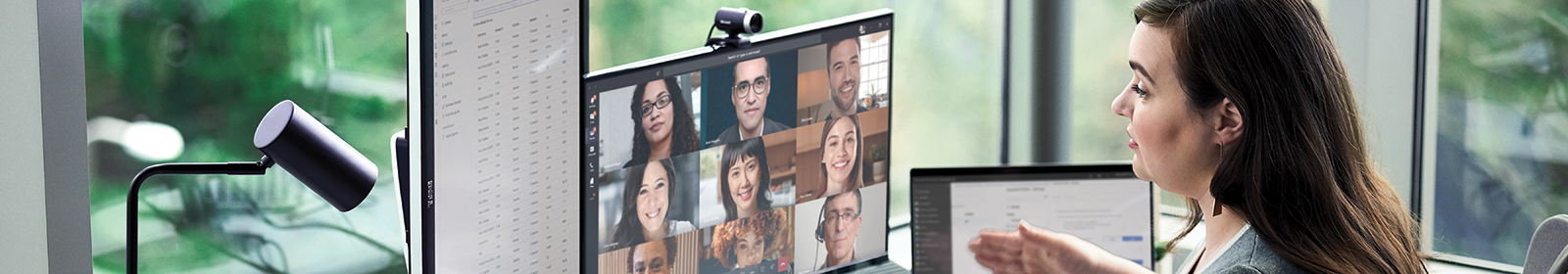 A seated woman gestures to a monitor with people in a Teams meeting