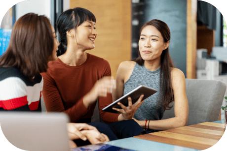 A person holds a tablet while talking to two colleagues