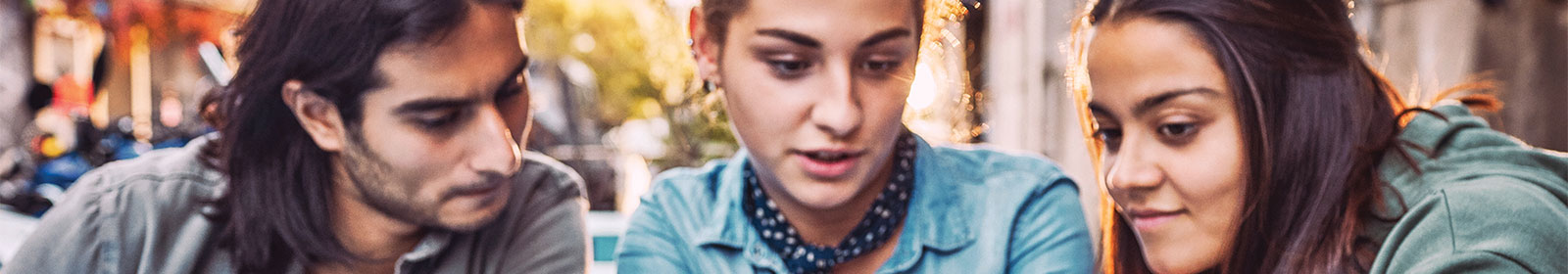 Three young adults sitting outside working on Surface