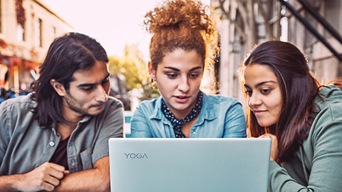 Three students gathered around laptop outside