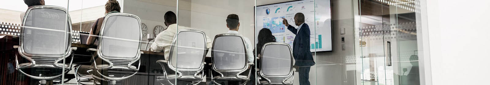 Business professionals at conference room table watching man give a presentation